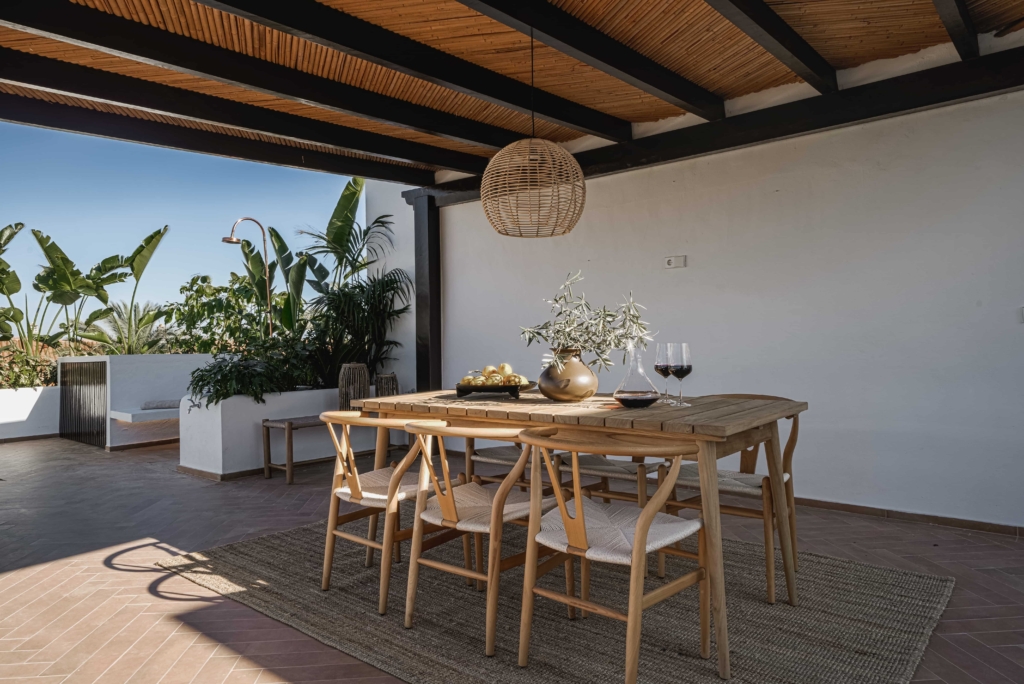 Dining area with wooden table and chairs under a pergola.